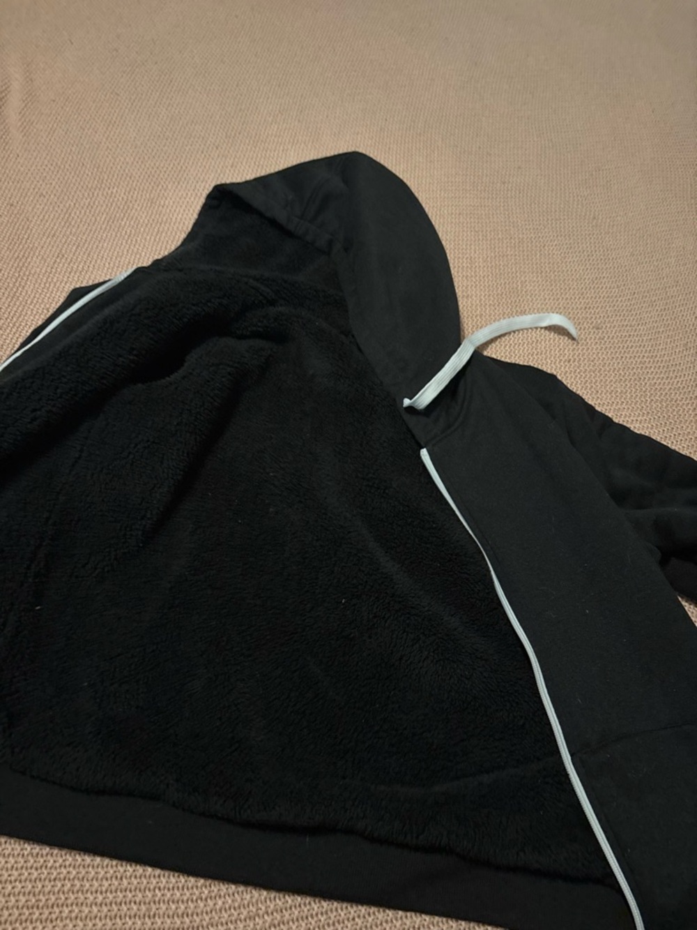 Black zip up hooded jacket with a Sherpa material lining the inside